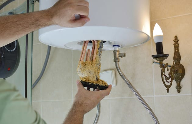 Technician removing mineral buildup from a water heater in San Jacinto