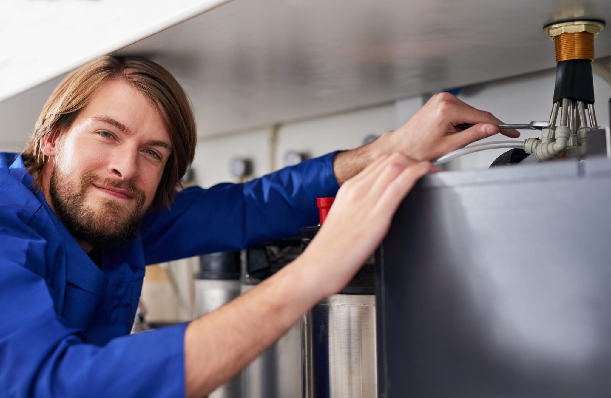 Technician servicing a residential water heater tank in San Jacinto