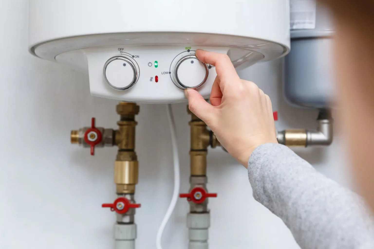 Homeowner adjusting the temperature controls on a water heater in San Jacinto